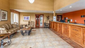 A reception area with a wooden reception desk, a sofa, a table with a bowl, and a chandelier. - Rodeway Inn Santa Rosa, NM (Santa Rosa)