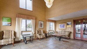 A spacious lobby with a high ceiling, large windows, and a chandelier. There are several sofas and a table in the center. - Rodeway Inn Santa Rosa, NM (Santa Rosa)