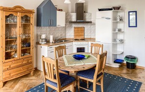 Enjoy cooking in this well-equipped kitchen with a central island, wooden cabinet, refrigerator, and stove.