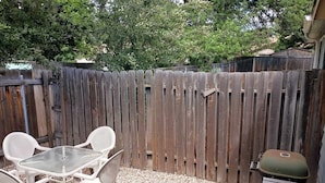 A patio area with a table and chairs, a grill, and a wooden fence. - Charming, Cozy Boise Duplex (Boise)