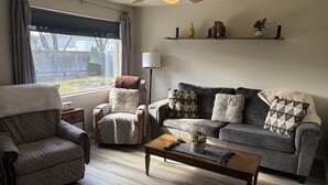 A living room with a sofa, armchair, and coffee table. - Charming, Cozy Boise Duplex (Boise)