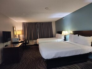 A hotel room with two beds, a desk with a computer, a TV, and a large window with curtains. - Baymont Inn & Suites by Wyndham Lincoln NE (Lincoln)