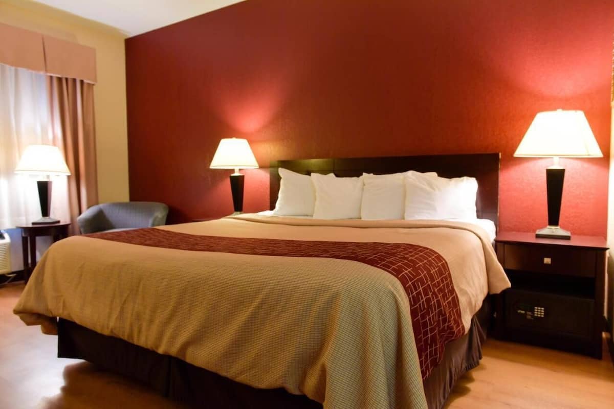 A hotel room with a bed, two bedside lamps, a chair, and a nightstand.
