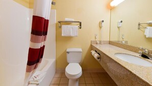 A bathroom with a white toilet, a sink with a mirror, and a shower curtain. - Baymont Inn & Suites by Wyndham Lincoln NE (Lincoln)