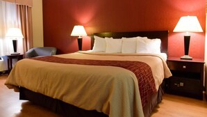 A hotel room with a bed, two bedside lamps, a chair, and a nightstand.