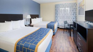 Quarto de hotel com duas camas, uma escrivaninha, uma cadeira, uma televisão e uma janela com cortinas.