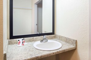A bathroom with a white sink, a mirror, and a countertop.