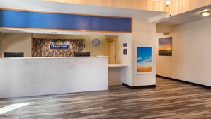 A reception desk with a Days Inn sign, a clock, and a painting of a sunset.