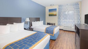 A hotel room with two beds, a desk, a chair, a TV, and a painting on the wall.