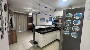 Eine moderne Küche mit weißen Schränken, einer schwarzen Arbeitsplatte und einem Kühlschrank mit dekorativen Magneten.