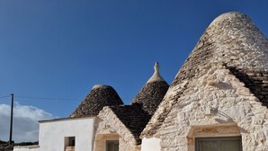 Ein traditionelles Steinhaus mit Kegeldach, einer Tür und einem kleinen Fenster.