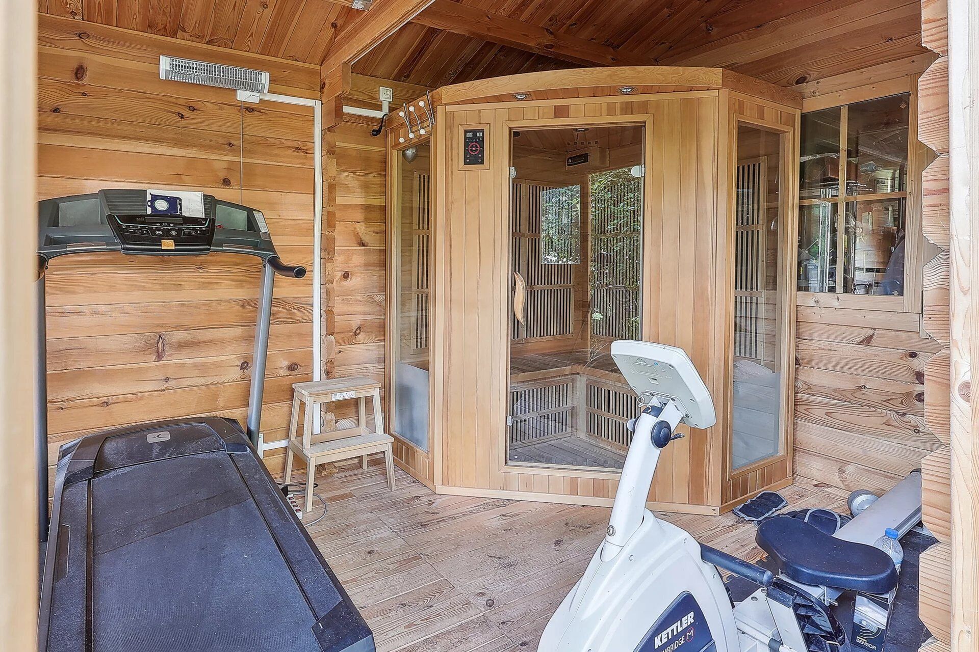 En træhytte med sauna, massagestol og en lille træskammel.