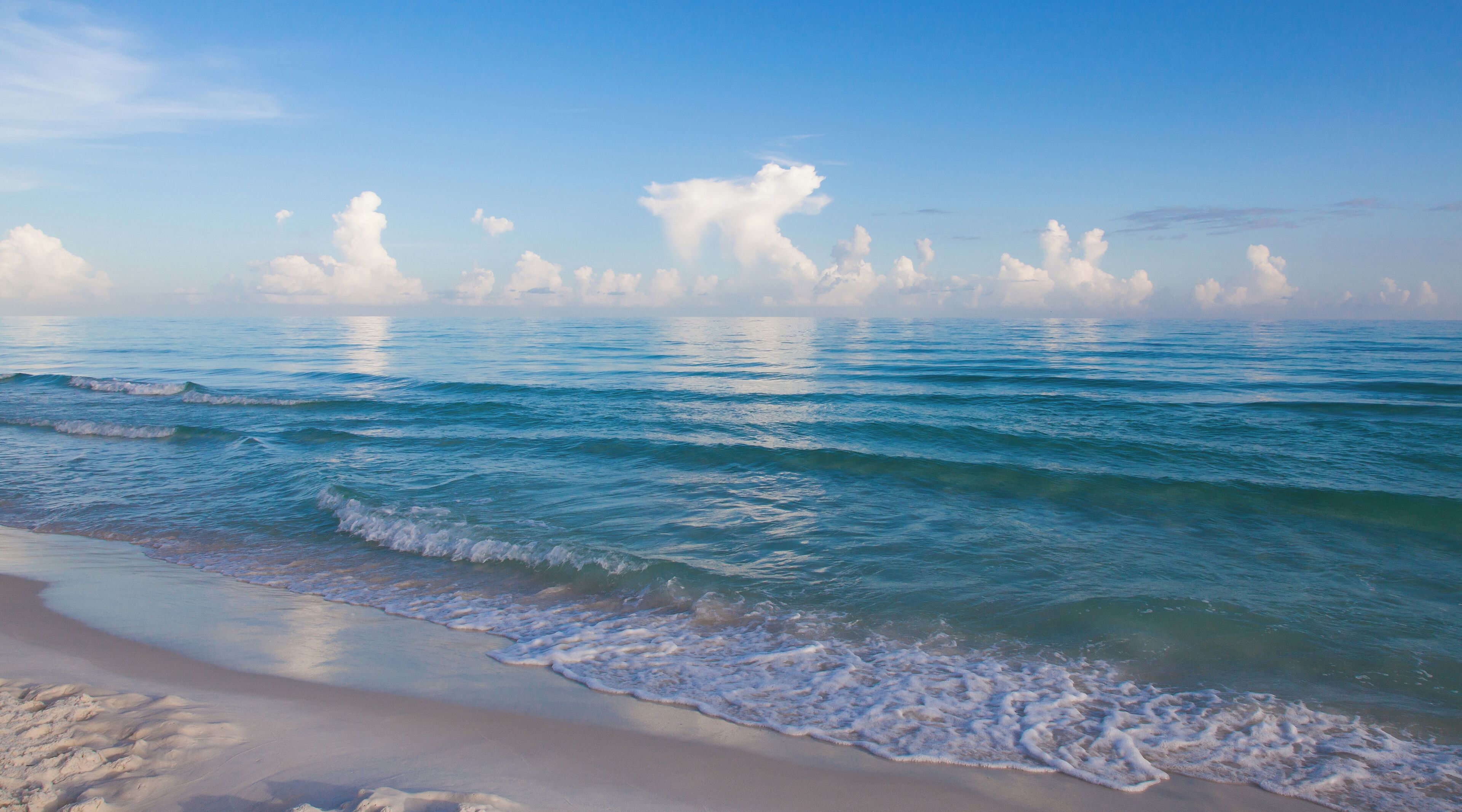 A beach with waves and a clear sky.