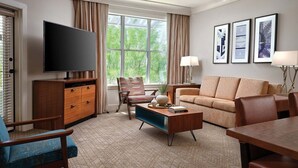 Una sala de estar moderna con una televisión de pantalla plana, un sofá, una mesa de centro y un comedor.