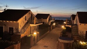 Uma rua estreita com edifícios de ambos os lados, com varandas e um caminho central.