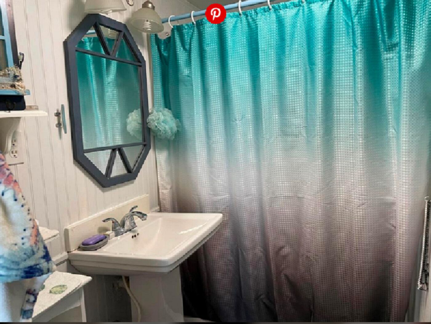 Ein Badezimmer mit einem weißen Waschbecken, einem Spiegel und einem türkisfarbenen Duschvorhang.