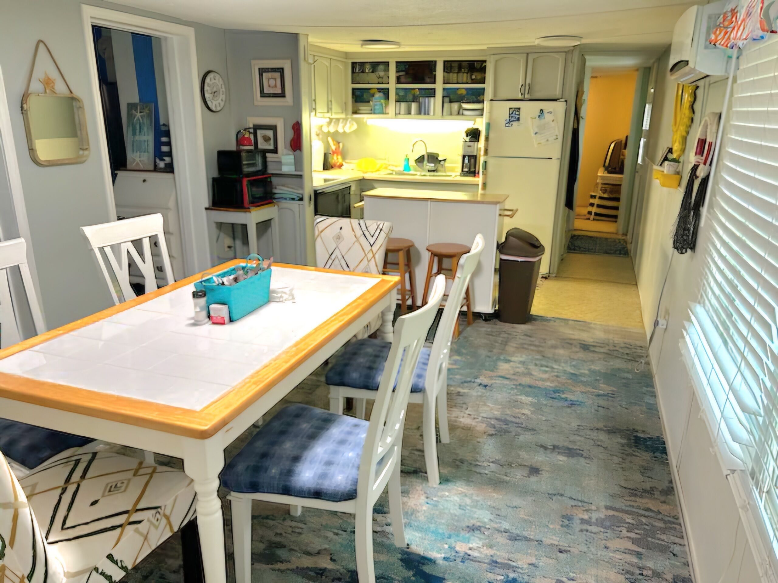 A compact kitchen with white cabinets, a central island, and a dining area with a wooden table and chairs.