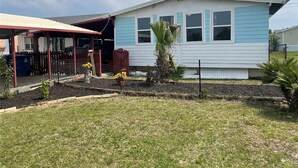 Een gelijkvloers huis met een overdekte veranda, een omheinde tuin en een kleine bloembed met bloemen en planten.