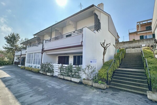 A two-story building with a balcony, a staircase, and a sign indicating a public space.