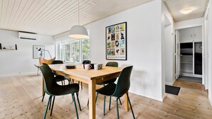 Un comedor moderno con una mesa de madera, sillas negras y turquesas, y un cartel grande en la pared.