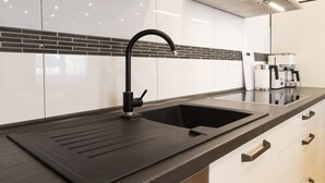 A modern kitchen with a black sink, white cabinets, and a black backsplash. - Haus Oselbach- Gemütlich, Zentral, Modern (Zweibrücken)