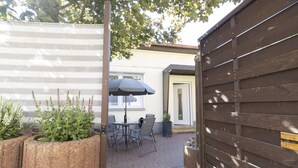 A patio area with a table and chairs, a potted plant, and a wooden fence. - Haus Oselbach- Gemütlich, Zentral, Modern (Zweibrücken)