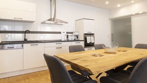 A modern kitchen with white cabinets, a wooden dining table, and black chairs. - Haus Oselbach- Gemütlich, Zentral, Modern (Zweibrücken)