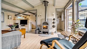 Un salon chaleureux avec une cheminée, un plancher en bois et une grande fenêtre.