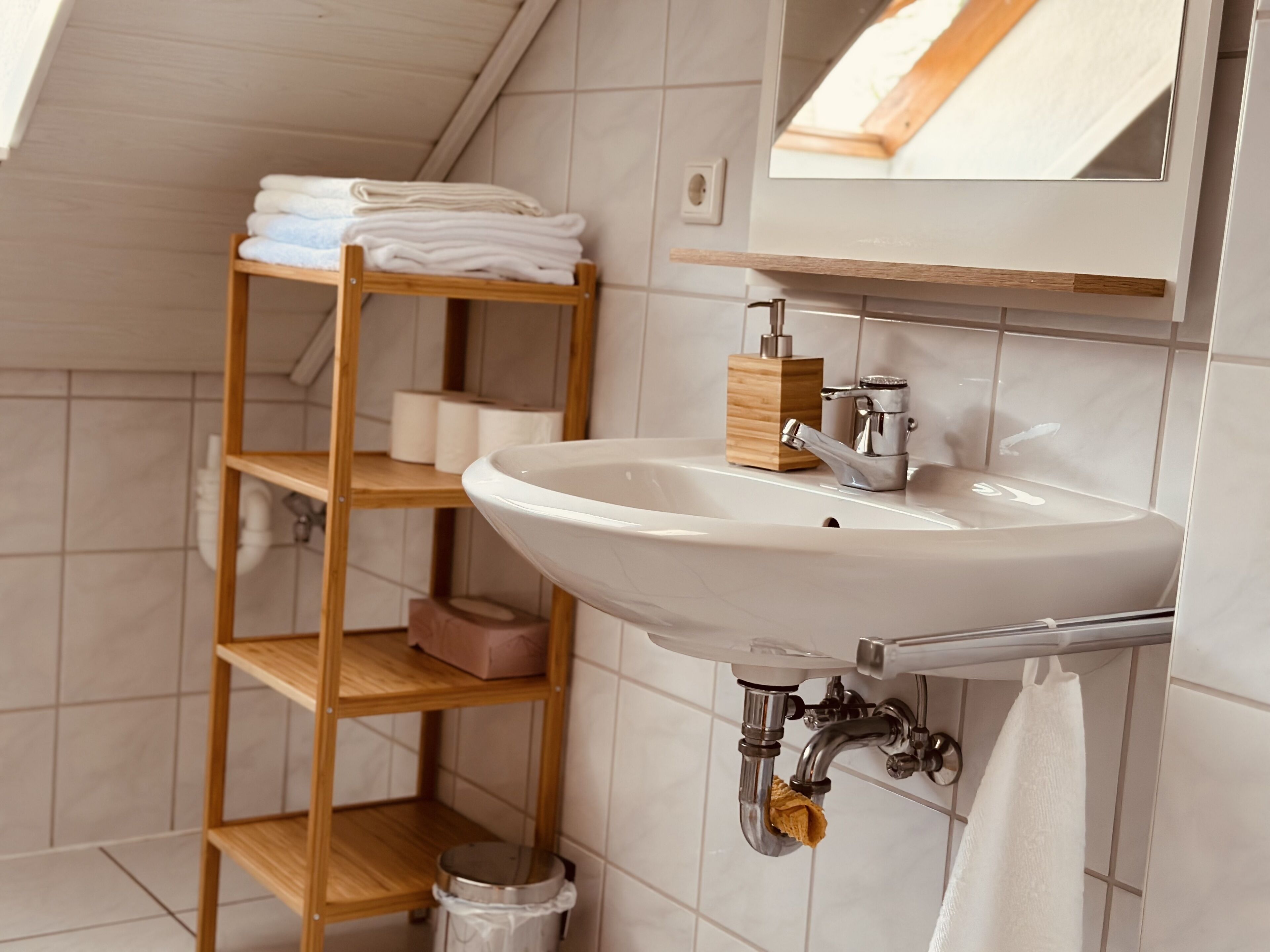 Een badkamer met een wit wastafel, houten planken en een spiegel.