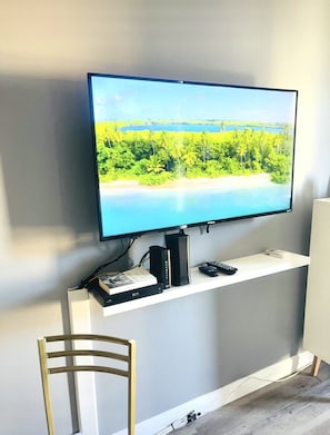 A flat-screen TV mounted on a white console with a remote control and a DVD player.