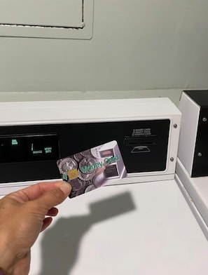 A hand holding a money card in front of a card reader.