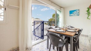 A dining area with a table set for four, a view of the sea, and a painting on the wall. - Nice apartment in Santa Pola with WiFi (Santa Pola)