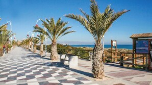 A paved walkway with palm trees, a checkered floor, and a view of the sea. - Nice apartment in Santa Pola with WiFi (Santa Pola)