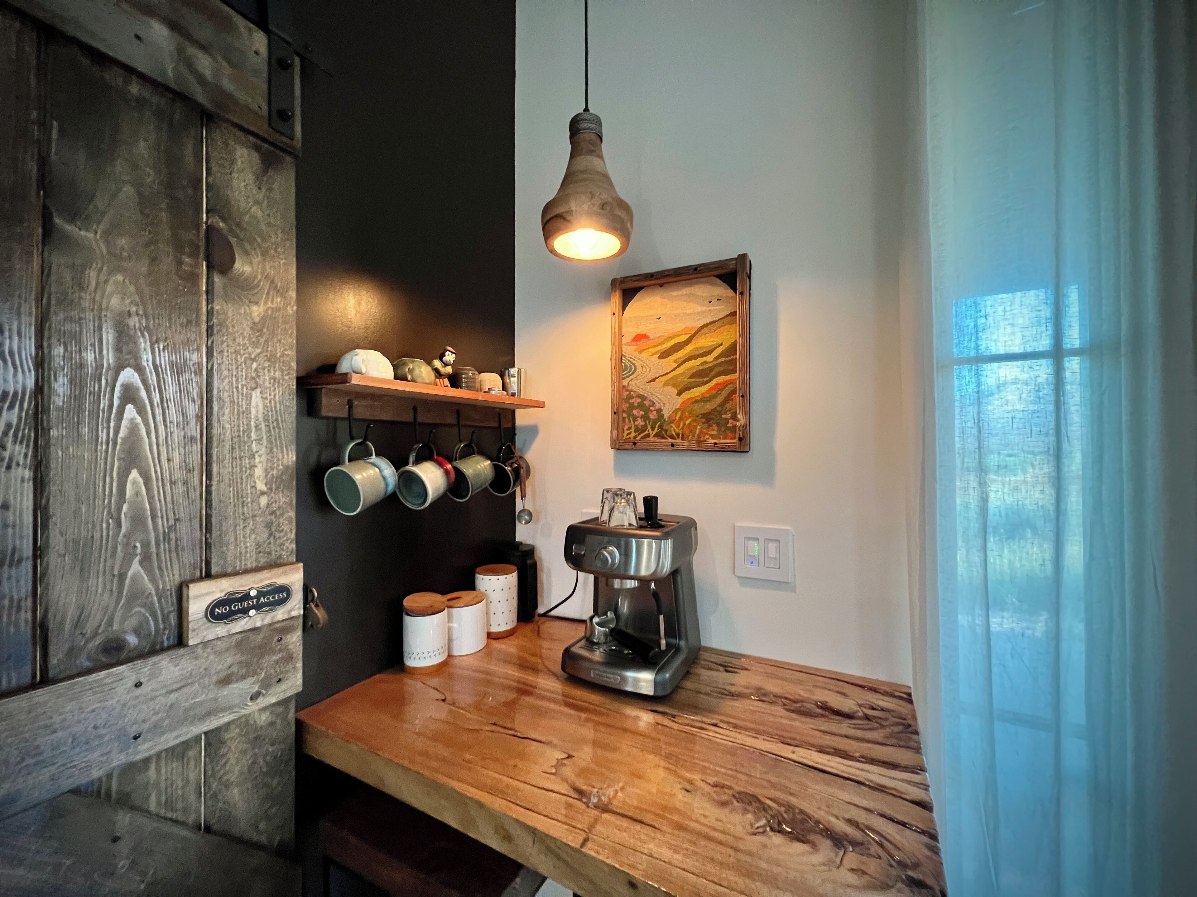 Een keuken met houten planken met mokken, een koffiezetapparaat en een bordje 'Geluidsrechten voorbehouden'.