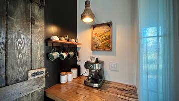 Een keuken met houten planken met mokken, een koffiezetapparaat en een bordje 'Geluidsrechten voorbehouden'.