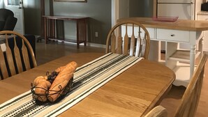 A dining area with a wooden table set for two, a kitchen with white cabinets, and a framed picture on the wall. - Quiet, 3 bedroom & 1 bath get-a-way. Near Lake Erie for fishing & skiing resorts (Albion)