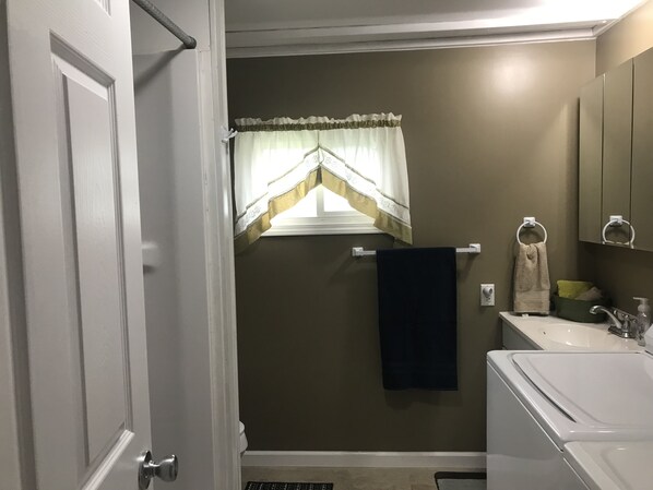 A bathroom with a white bathtub, a sink with a green soap dispenser, and a towel rack with two towels. - Quiet, 3 bedroom & 1 bath get-a-way. Near Lake Erie for fishing & skiing resorts (Albion)