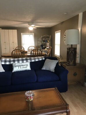 A living room with a dark blue sofa, a coffee station, wooden chairs, and a lamp. - Quiet, 3 bedroom & 1 bath get-a-way. Near Lake Erie for fishing & skiing resorts (Albion)