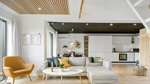 A modern living room with a sofa, armchair, and coffee table, a kitchen in the background, and a large window with curtains. - Awesome home in Haderslev with WiFi (Haderslev)