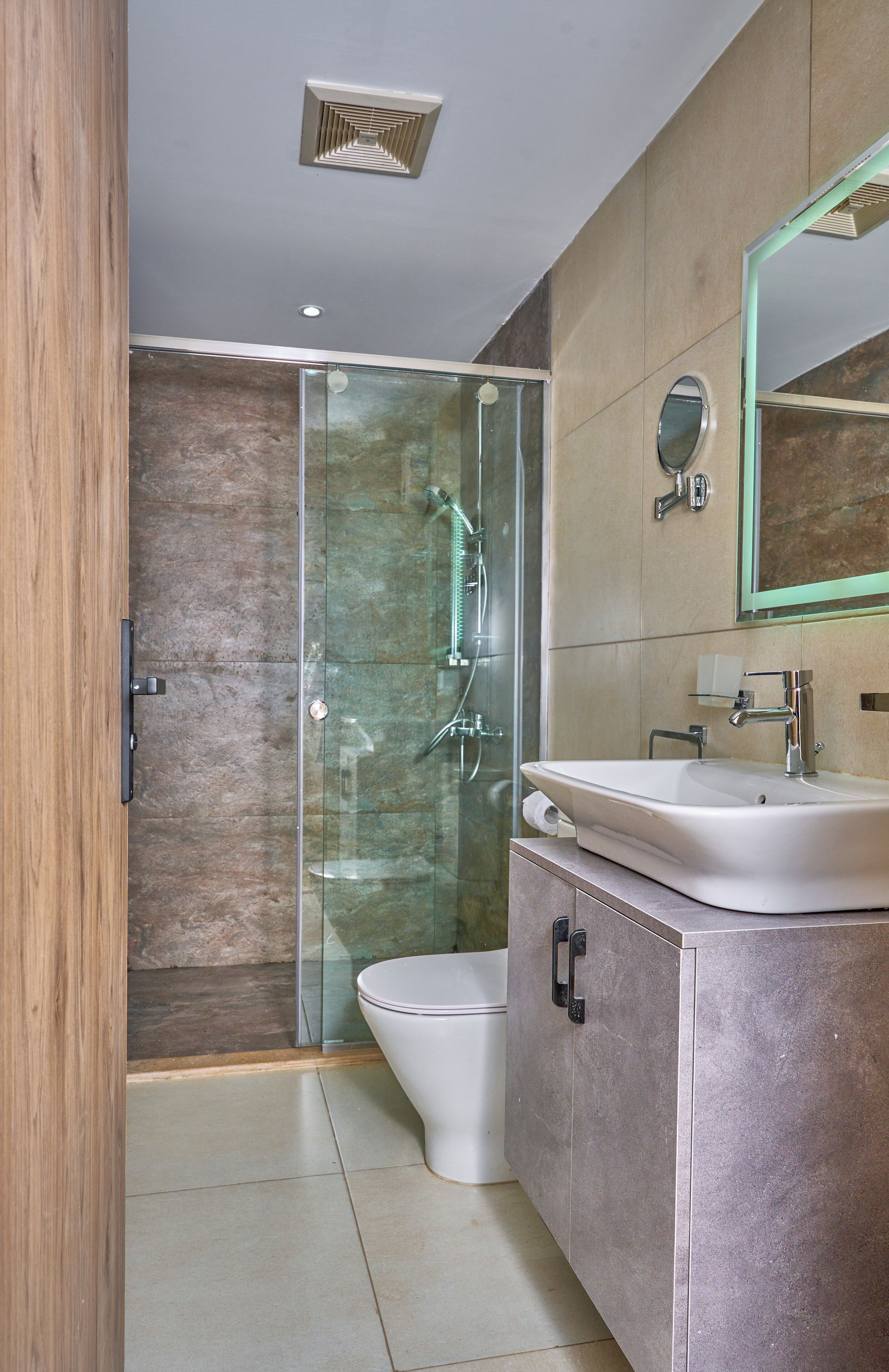 Un baño moderno con ducha envuelta en vidrio, inodoro blanco y tocador con espejo.