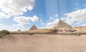 A desert landscape with three pyramids and a clear sky.