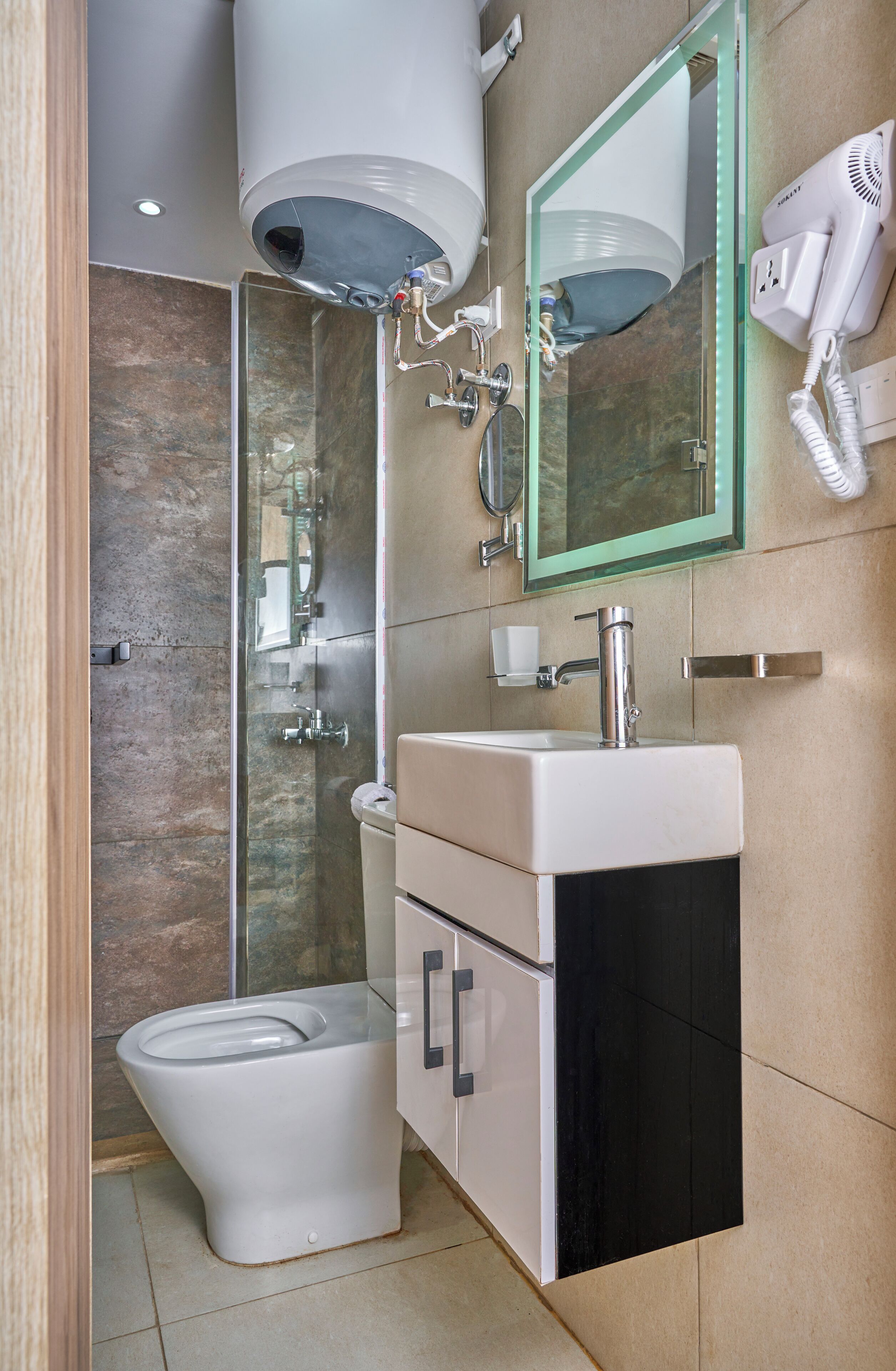 A modern bathroom with a toilet, sink, mirror, and hairdryer.