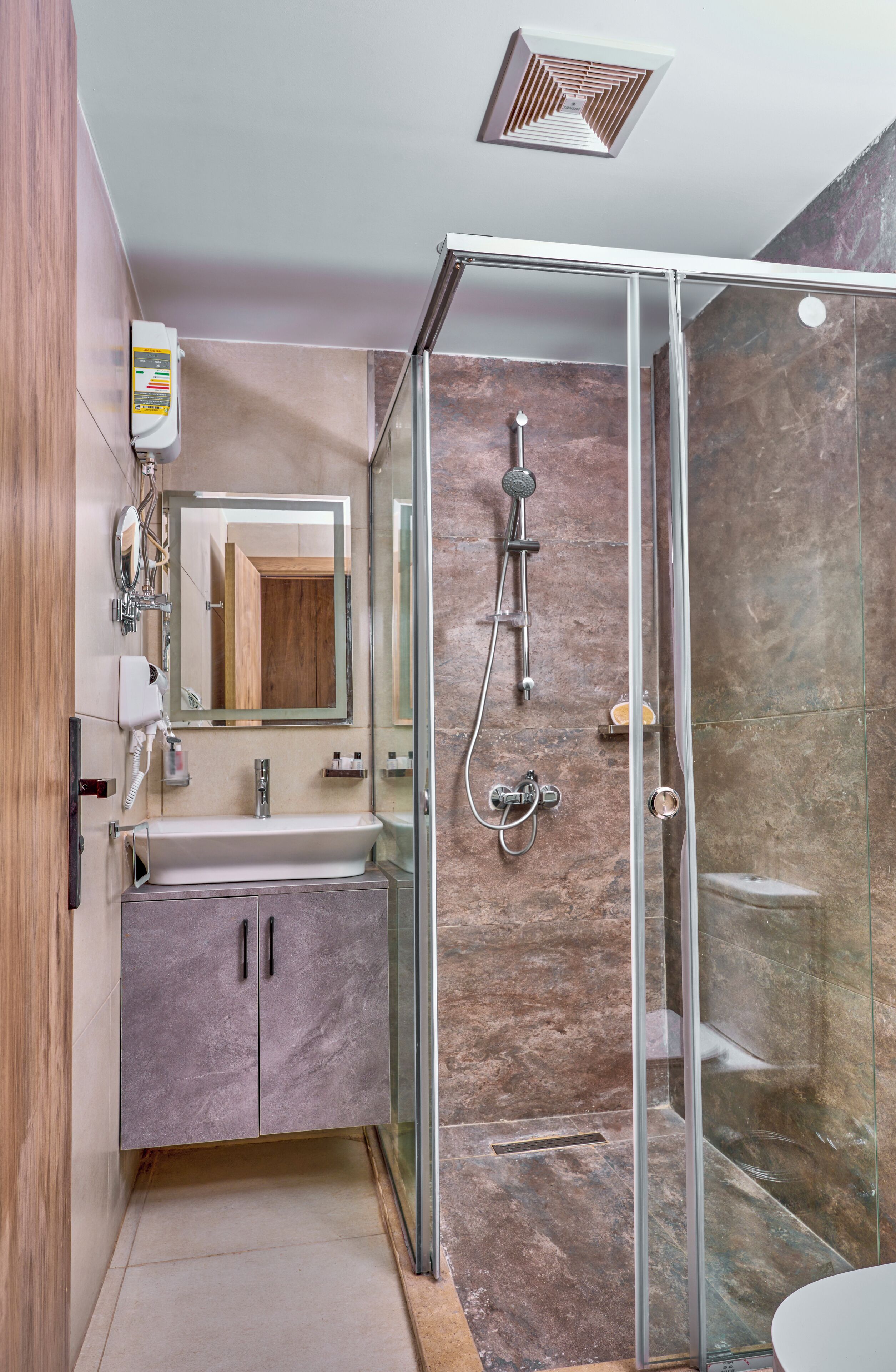 Een moderne badkamer met een douchecabine van glas, een wastafel met spiegel en een ingebouwde kast.