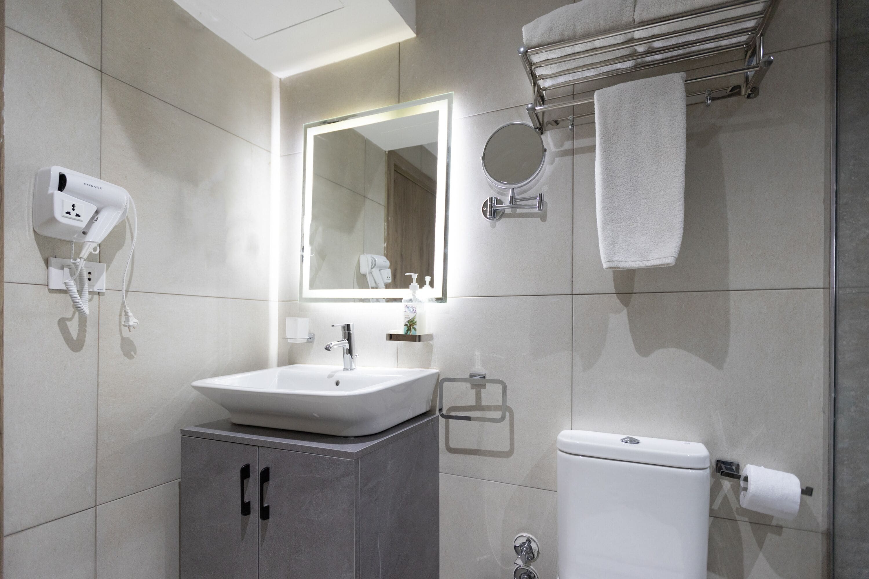 A modern bathroom with a sink, mirror, towel rack, and toilet.