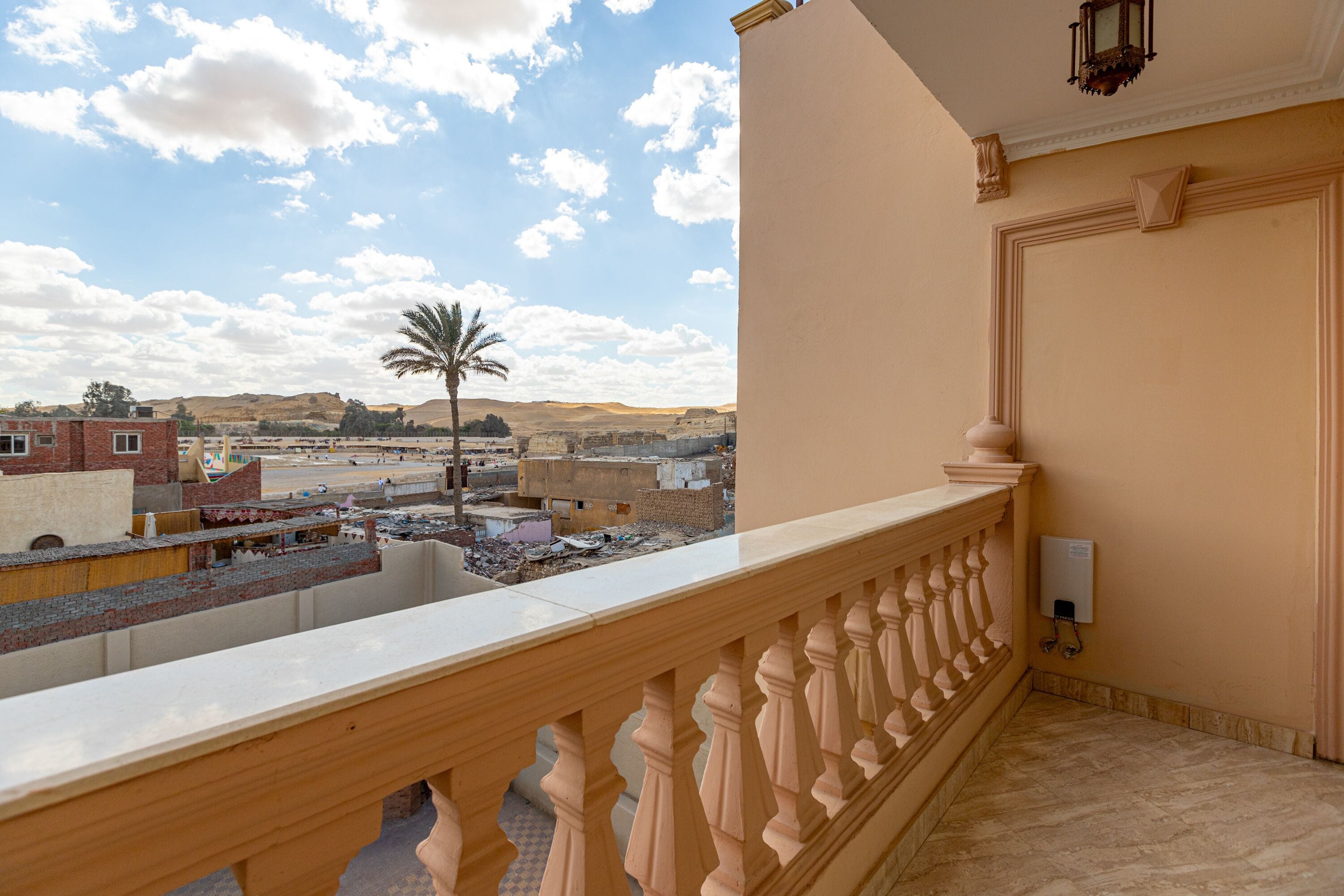 A balcony with a view of a cityscape, including buildings and a palm tree.