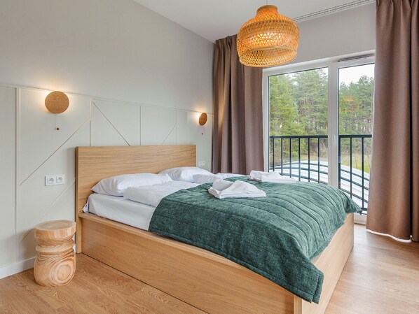 Et moderne soveværelse med en træseng, et grønt tæppe og udsigt til en balkon med gelænder.
