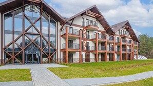 Un edifici modern de diversos pisos amb grans finestres de vidre i balcons de fusta.