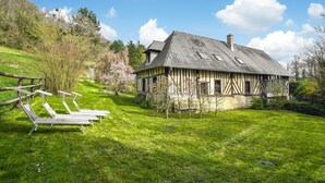 A traditional chalet with a sloped roof, a wooden deck with chairs, and a lush green garden. - Awesome home in St.Marguerite d.Loges with sauna (St.Marguerite d.Loges)