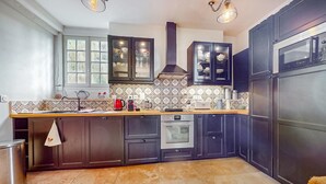 A modern kitchen with dark cabinets, a stainless steel refrigerator, an oven, and a tiled backsplash. - Awesome home in St.Marguerite d.Loges with sauna (St.Marguerite d.Loges)