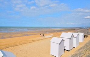 A beach with white beach huts and a lifeguard tower.